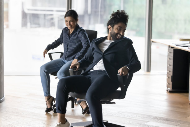 印度同事在休息时间坐在办公椅上开玩笑图片下载