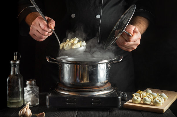 厨师在餐厅厨房里用平底锅准备意大利饺子。一个厨师工作时的手特写图片下载