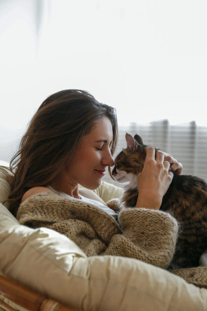 肖像的年轻女子抱着可爱的挪威猫与绿色的眼睛。雌猫抱着她可爱的长毛小猫。背景，复制空间，关闭。图片下载
