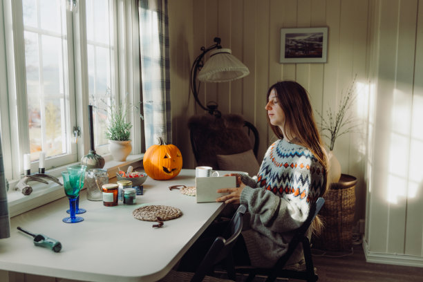 一个穿着羊毛衫的女人，在惬意的万圣节早晨看书图片下载