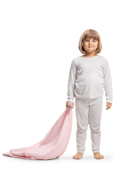 一个穿着睡衣的小女孩拿着一条粉红色的毯子图片下载