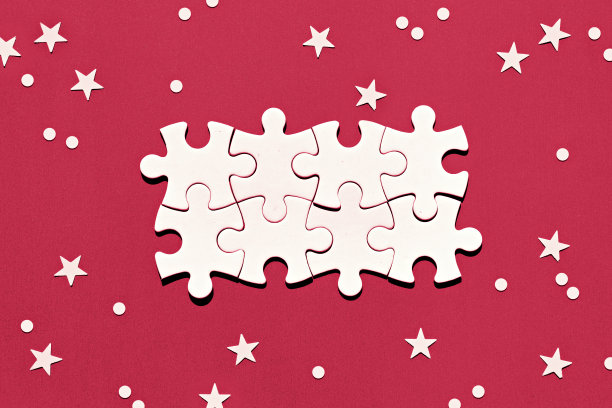 拼图碎片在红色背景与雪花和星星的中间。圣诞冬季抽象节日背景与空间的圣诞问候。图片下载