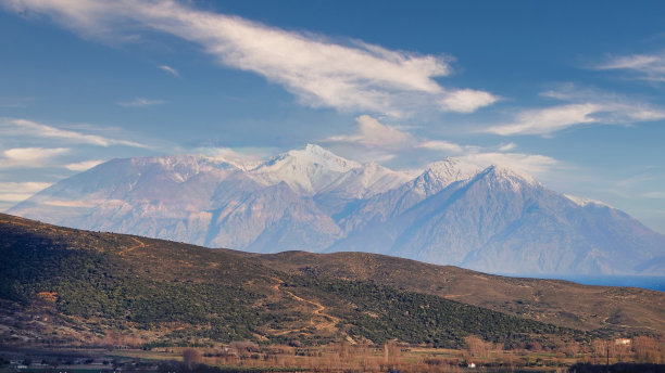 透过雾云和雪山可以看到 Gökçeada 的田园诗般的景色和火山山图片下载