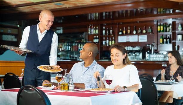 友好的服务员带来订购的披萨夫妇在披萨店图片下载