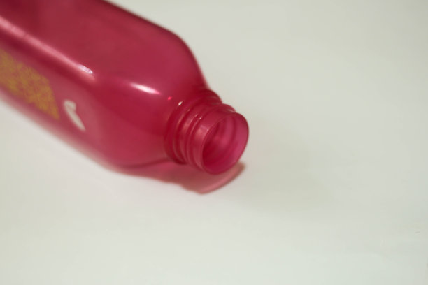 空的饮料瓶，粉色或紫色孤立在白色背景上。对角线。副本的空间。图片下载