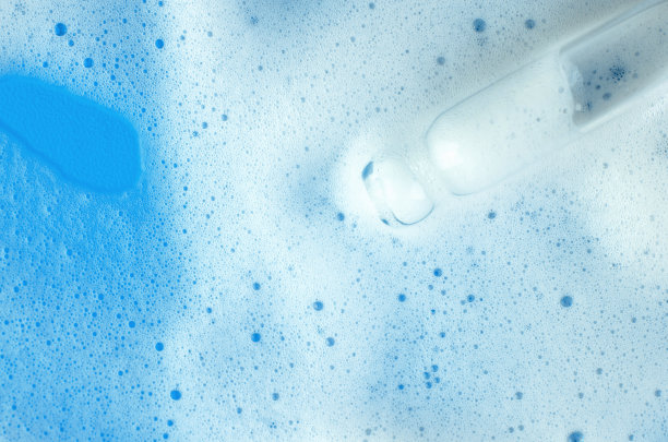 蓝色背景上的白色泡沫和吸管。白色洗发水泡沫或洗衣泡沫的微距照片图片下载