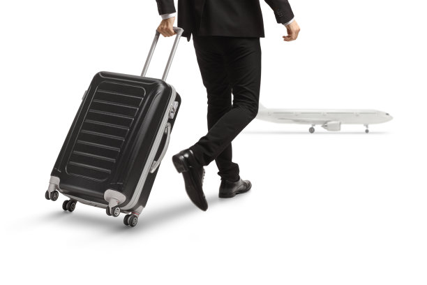 一个男人拉着行李箱走向飞机的后视图图片下载