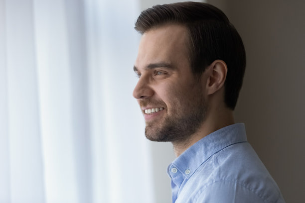 微笑的商人站在窗边，遥望远方，谋划着图片下载