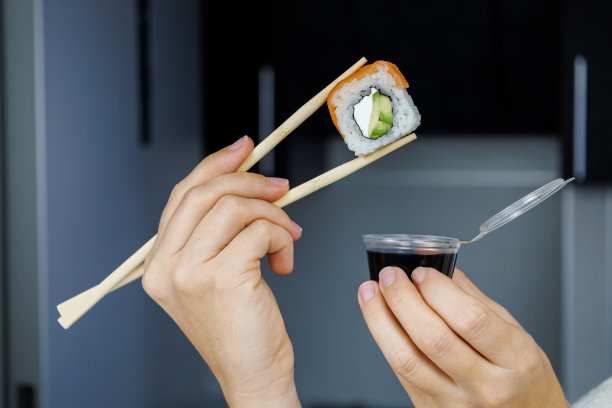 日本人滚费城。这个女孩正用筷子夹着寿司。模糊的背景图片下载