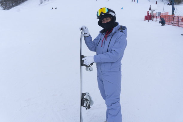 年轻女子在滑雪胜地玩滑雪板的照片图片下载
