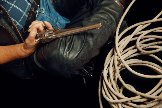 牛仔坐在靠近套索的地板上，手里拿着一把左轮手枪图片下载