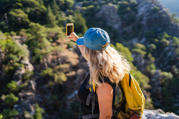 一名成年女子在山上徒步，用手机图片下载