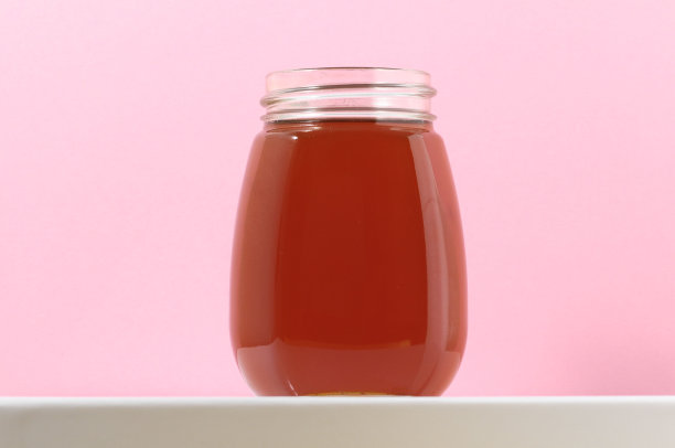 粉红色背景上的满满一罐蜂蜜图片下载
