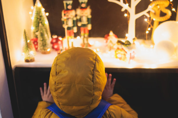 小朋友小朋友站在商店橱窗前，用店面的橱窗、展柜、玻璃柜、店面装饰新年圣诞，小朋友和圣诞店市场概念、照明图片下载
