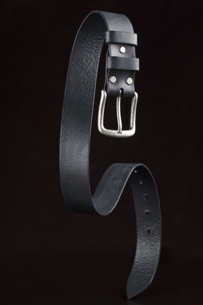 深色背景的黑色皮带。皮革产品。图片下载
