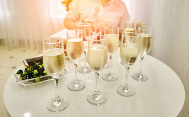 女服务员把起泡的白葡萄酒分发给客人。图片下载
