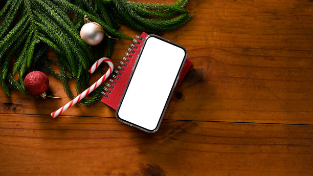 俯视图，智能手机模型与圣诞饰品和复制空间的木质桌面图片下载