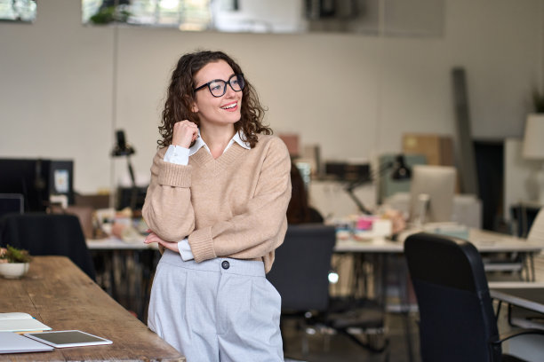 年轻积极快乐的职业商业女性站在办公室。图片下载