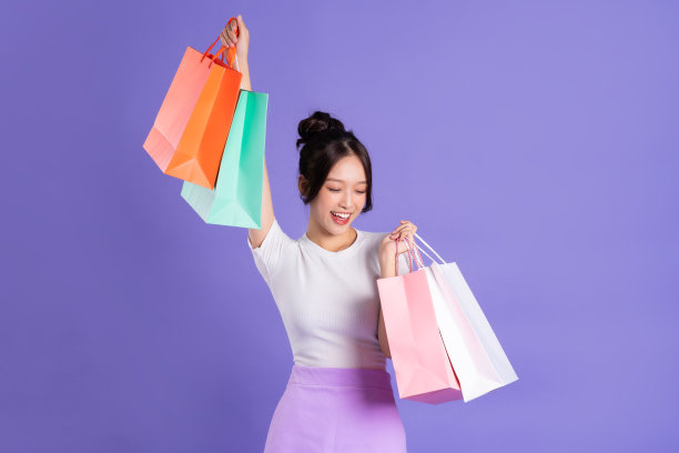 美丽的亚洲女孩拿着购物袋在紫色背景上摆姿势图片下载