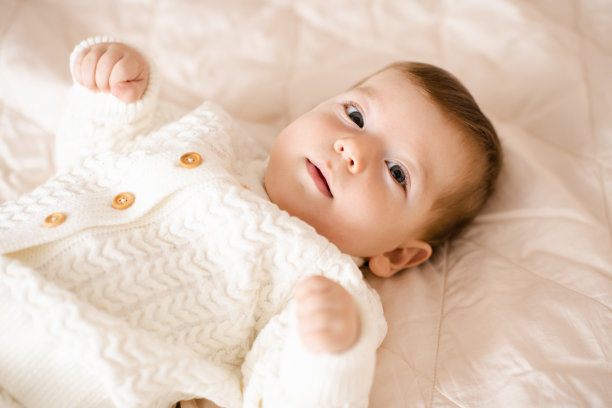 小男孩躺在床上，近距离看着摄像机。图片下载