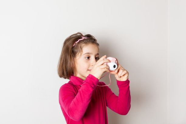 小女孩用白色背景的玩具相机拍照图片下载