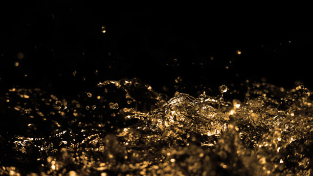 高速特写图像的油液从柴油汽油飞溅和移动到空气上的黑色背景。燃料液体的动力，活跃和强大。工作室拍摄优质金色色调。图片下载