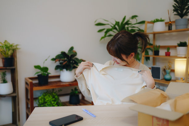 一名亚洲妇女正在扫描包装盒上的二维码。图片下载