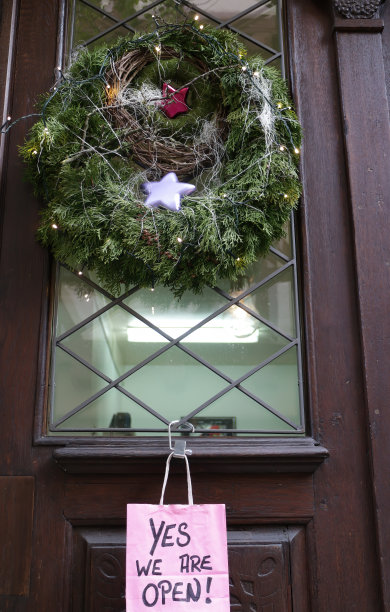一家商店的前门，有一个圣诞花环和一个敞开的招牌图片下载