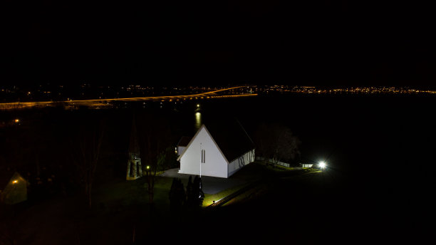 在多云的天空背景下，工业建筑映衬着岸边的景色。挪威。图片下载