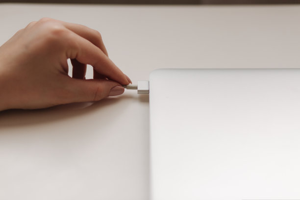 人手握电脑笔记本电源插头。笔记本电脑的权力。充电器图片下载