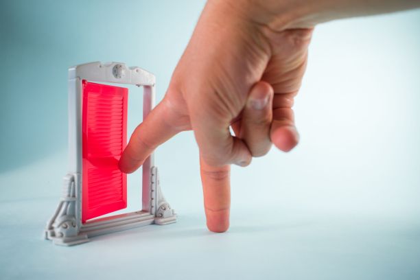 手触摸一个粉红色的迷你门模型在白色的背景在近距离-玩具配件的概念图片下载