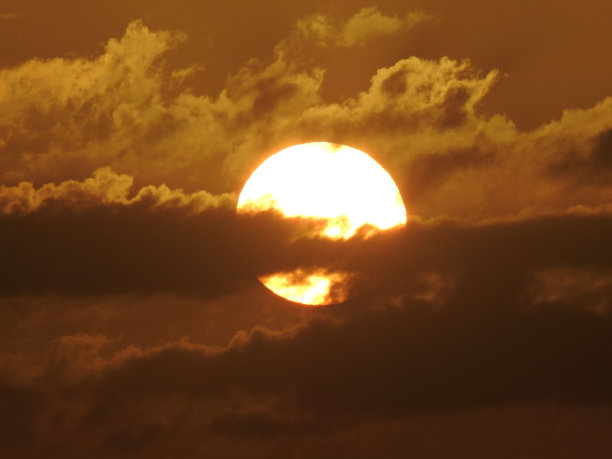 密集云层后面燃烧的圆形太阳特写图片下载
