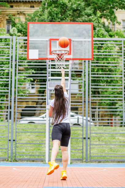 年轻的女运动员正在现代化的户外篮球场上训练打篮球。快乐的女人图片下载