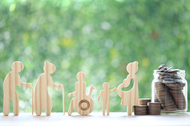 共同基金，爱情夫妇，老年人和轮椅上的人。孕妇与一堆硬币钱在玻璃瓶子上自然绿色的背景，为残疾人和养老金退休省钱的概念图片下载