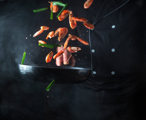 专业厨师在平底锅里煮虾和蔬菜。烹饪海鲜、健康素食和深色背景的食物。运动中的冻结。免费广告位图片下载