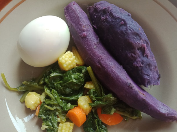 棕色盘子里的健康食物包括鸡蛋、紫色块茎和各种蔬菜，如小玉米、芥末和胡萝卜图片下载