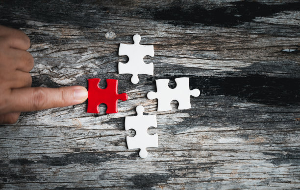 女人手中的拼图。白色细节拼图拼图片在木制背景。作为业务团队一起工作的概念。参与其中，为成功而努力。图片下载