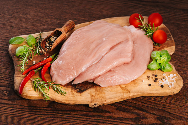 用香料和香草把生火鸡片放在砧板上。烹饪原料。天然健康食品理念。前视图。火鸡片放在木制背景上，加上香料。图片下载