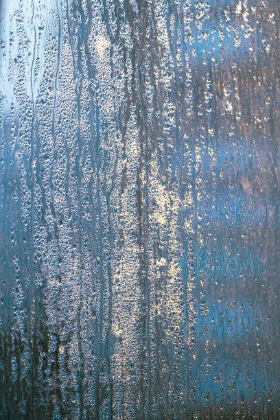 冬天玻璃薄雾的质感。窗户上的阳光下凝结的水珠。图片下载