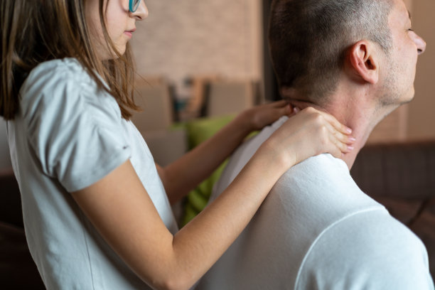 女儿在客厅给父亲按摩脖子。男性有背部疼痛和颈部外伤。疲劳中年男子触摸颈部炎症区，有办公室综合症。图片下载