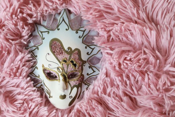 一个白色假面舞球面具孤立在粉红色蓬松的背景特写图片下载