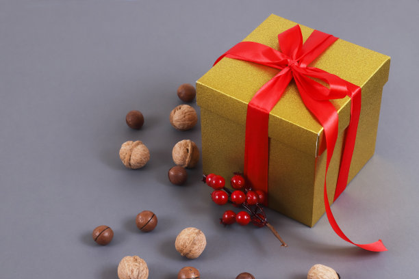 金色牛皮纸礼盒红丝带和坚果在灰色背景图片下载