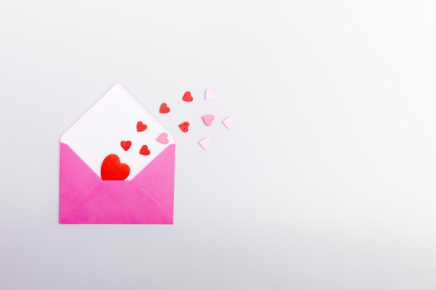 粉红色的信封和灰色背景上的爱心。情人节的概念，爱情，约会和婚礼。情书的象征。图片下载