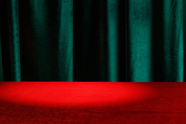 现代的背景是空的红布桌子和绿色的天鹅绒窗帘。模板广告，演示。亮点图片下载