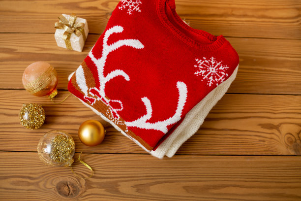 温暖的圣诞毛衣。冬季针织毛衣与图案的木制背景与圣诞装饰。一叠温暖的圣诞毛衣。俯视图图片下载