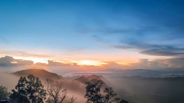 从印度尼西亚东爪哇岛的Bromo Tengger Semeru国家公园的观测点上看到的日出时笼罩在薄雾中的山区。图片下载