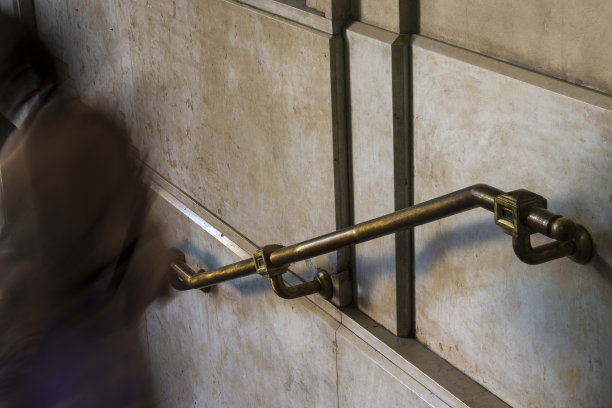 金属老式栏杆，固定在墙上。还有一个人，走下楼梯，在照片中被他的动作高度扩散，那是要从照片中走出来的。扶手-扶手图片下载