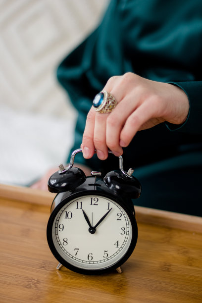 桌子上有一个复古闹钟，女孩从上面拿着闹钟。时间。图片下载