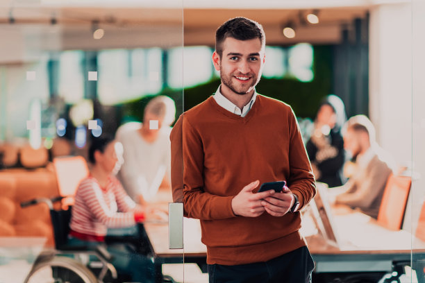 年轻英俊的商人自信地站在办公室，在他的团队面前图片下载