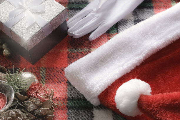 圣诞节的背景。礼盒，圣诞老人帽，白色手套和装饰蜡烛上的格子格纹图片下载